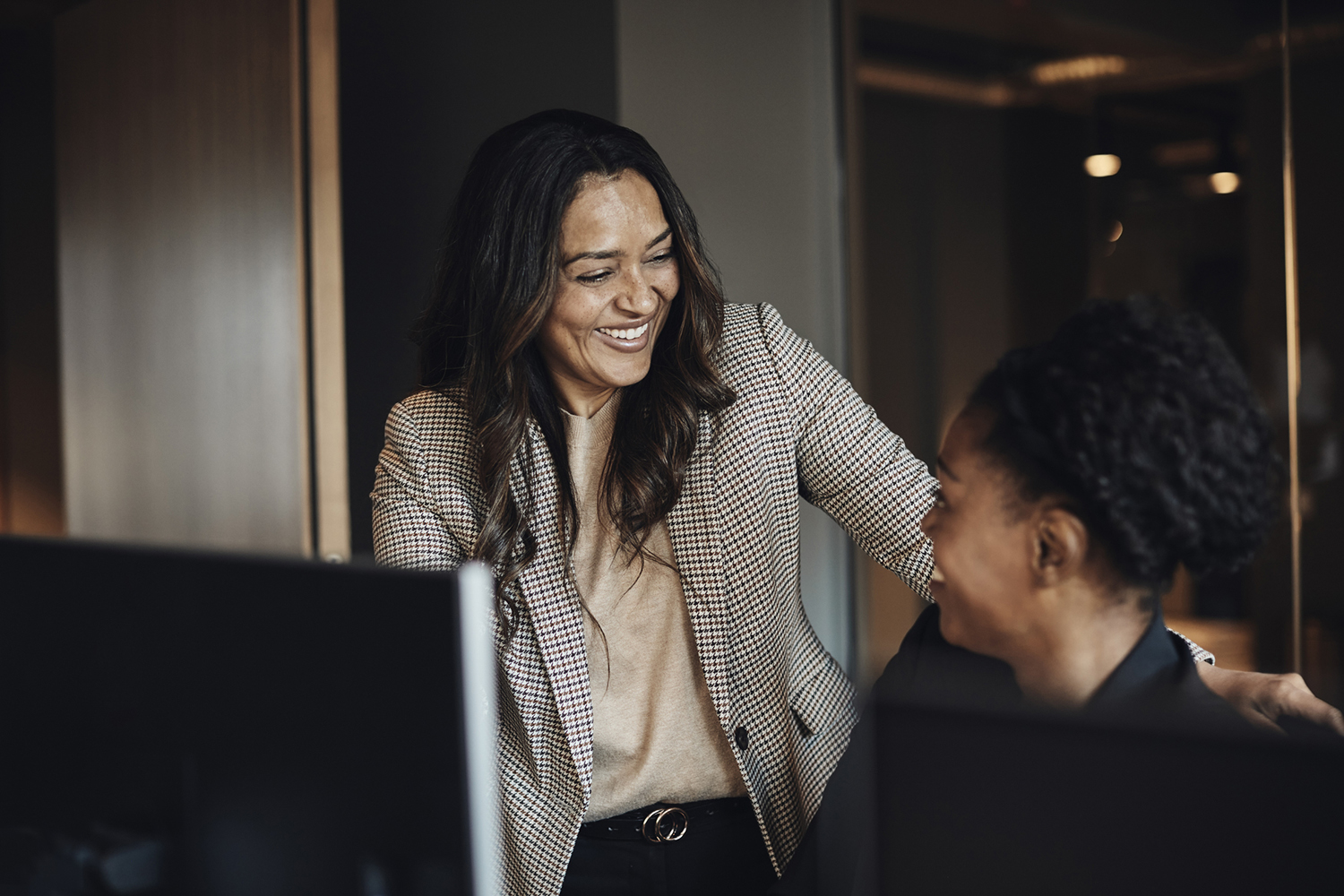 Two happy female business colleagues communicating with each other.