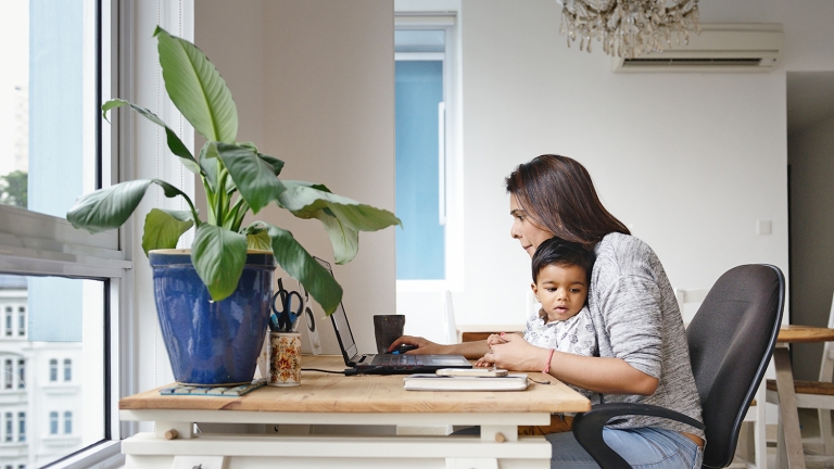 Woman working from a home office desk with her son.