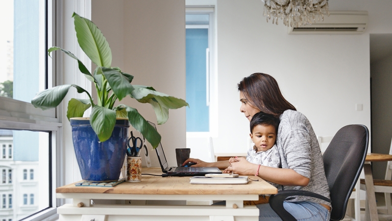 Woman working from a home office desk with her son. Woman working from a home office desk with her son.