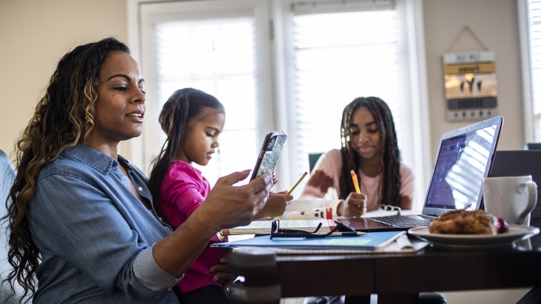 Mother working from home while daughters homeschool.