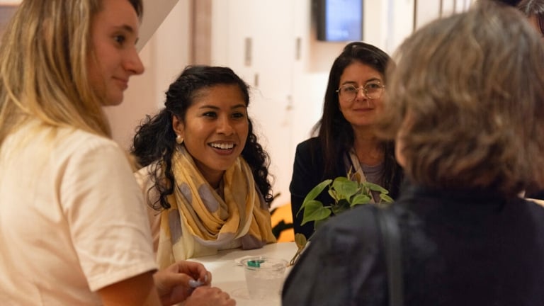 Women conversing at a table, fostering connection and collaboration through their engaging dialogue.