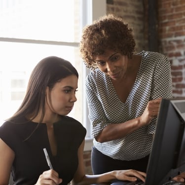 Two Businesswomen Working On Computer In Office