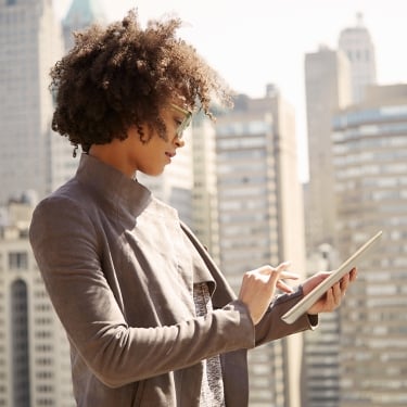 Businesswoman on rooftop holding a tablet computer.