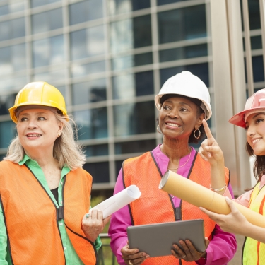 Multi-ethnic and mixed age team of female engineer or architect team up to work on a construction project in a downtown city location.