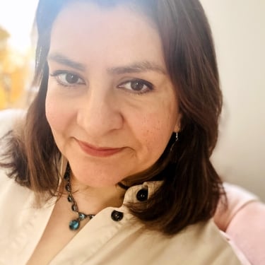 Claudia Franco with shoulder-length brown hair wearing a cream-colored blouse and a beaded necklace, smiling softly at the camera in a relaxed setting. Claudia Franco with shoulder-length brown hair wearing a cream-colored blouse and a beaded necklace, smiling softly at the camera in a relaxed setting.